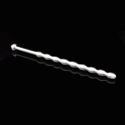 A shiny, silver-colored penis plug with a beaded rod and a rounded, flat end. It is shown against a black background.